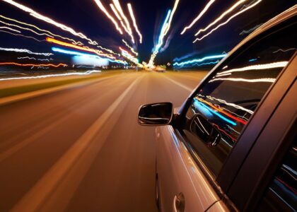 Car traveling down a city highway at night, representing the fast-paced nature of driving and the importance of non-owner car insurance in Indiana.