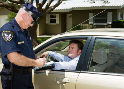 Police officer writing a citation for a driver in a car, illustrating traffic violations relevant to the difference between SR22 and FR44 insurance.