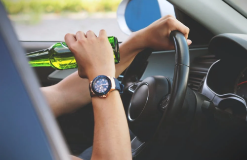 A person consuming beer while driving