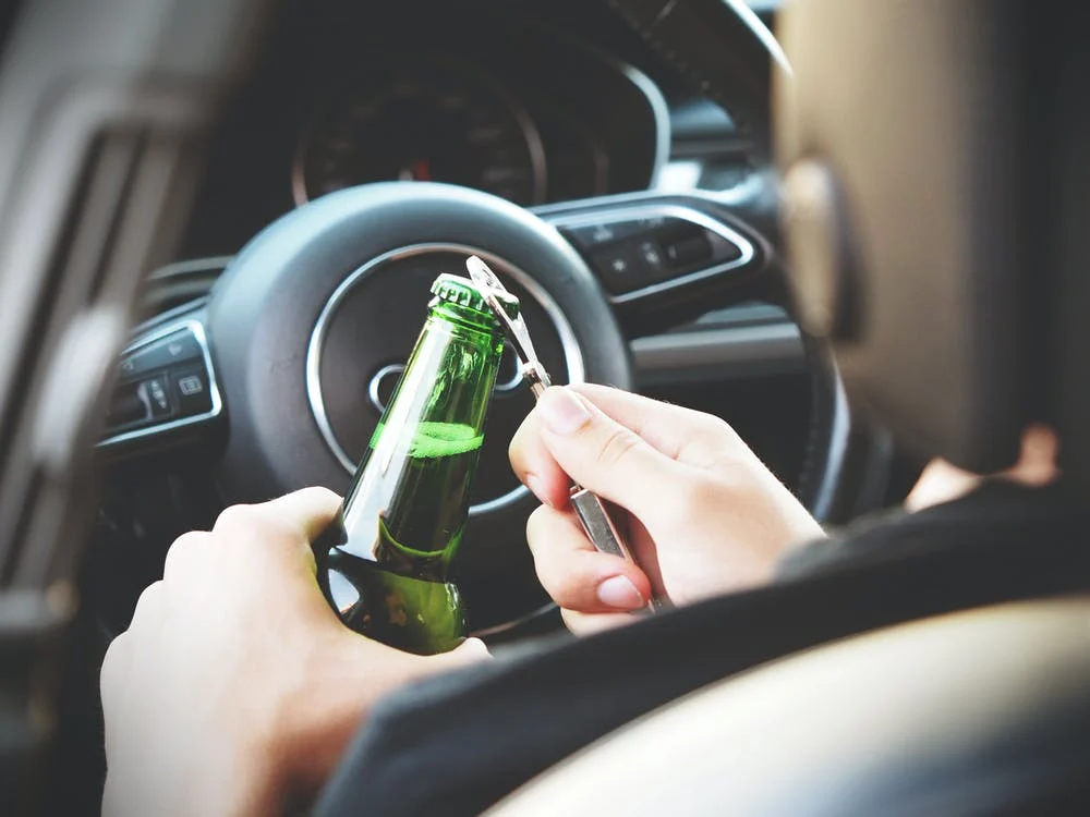 A driver opening a cold brew behind the wheel