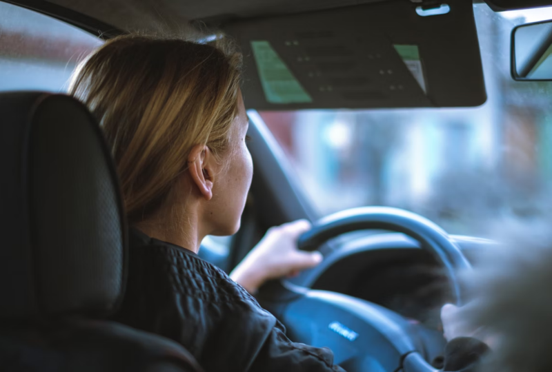 A young woman driving a car with Virginia FR-44 insurance.