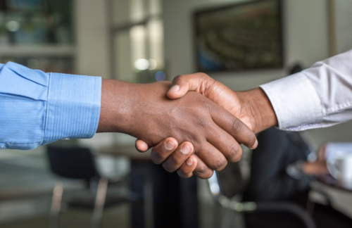 An insurance agent shakes hands with a client who purchased an Oregon high-risk auto insurance policy.