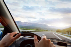 Person with hands on steering wheel of a car