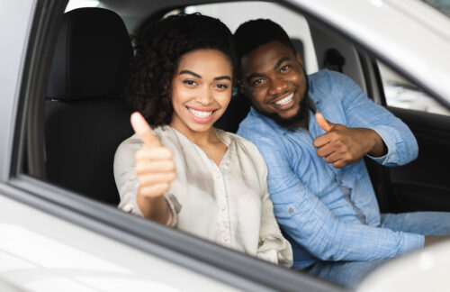 Two happy people in a car gesturing thumbs up after driver's license reinstatement with FR44 DUI insurance.