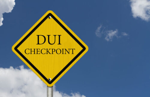 A yellow DUI checkpoint sign in Florida with blue sky and clouds in the background.