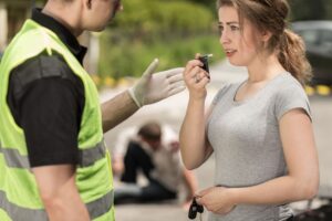 A young woman is taking a breathalyzer test for Florida DUI after a car accident.