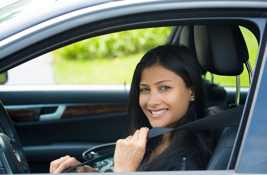 A smiling woman with Oregon owner or non-owner SR-22 insurance behind the wheel of her car.