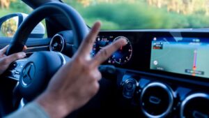 A driver behind the wheel making a victory sign after getting a non-owner auto insurance policy.