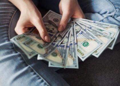 Person holding a fan of hundred-dollar bills, symbolizing the financial penalties and costs associated with DUI fines in Florida.