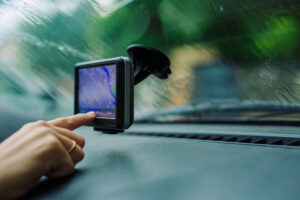 A Tennessee driver touching the screen of a hands-free cell phone device mounted on the windshield in her car.