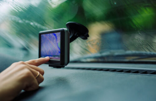 A Tennessee driver touching the screen of a hands-free cell phone device mounted on the windshield in her car.