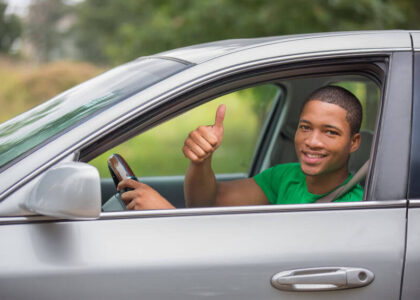 A happy young man driving his car after getting affordable Indiana SR22 insurance.
