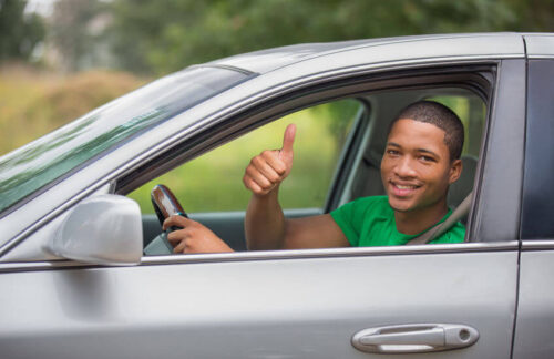A happy young man driving his car after getting affordable Indiana SR22 insurance.