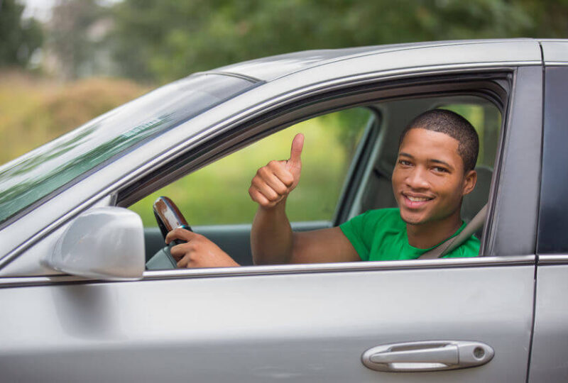 A happy young man driving his car after getting affordable Indiana SR22 insurance.