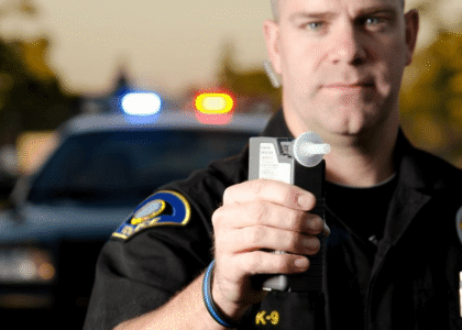 A traffic cop holds a breathalyzer device to test a driver for DUI in relation to requiring Vermont SR-22 insurance for license reinstatement.