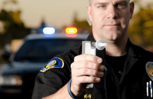 A traffic cop holds a breathalyzer device to test a driver for DUI in relation to requiring Vermont SR-22 insurance for license reinstatement.
