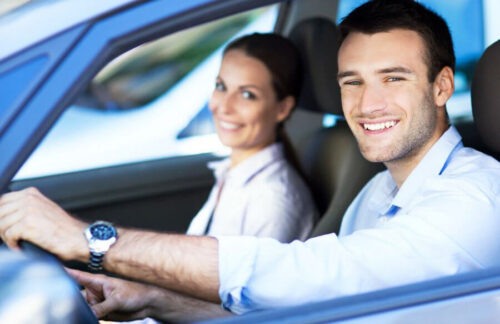 A smiling male driver at the wheel of his car who has obtained SR-22 insurance for license reinstatement.