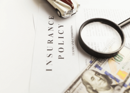 A photo of an insurance policy, cash, a toy car and magnifying glass represent obtaining an Oregon SR22 insurance policy to reinstate your license.