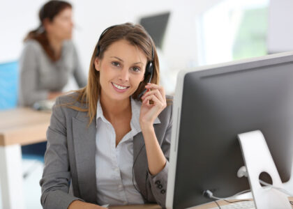 A smiling female SR22 insurance agent on the phone assisting a customer needing a Tennessee SR22 out-of-state insurance filing.