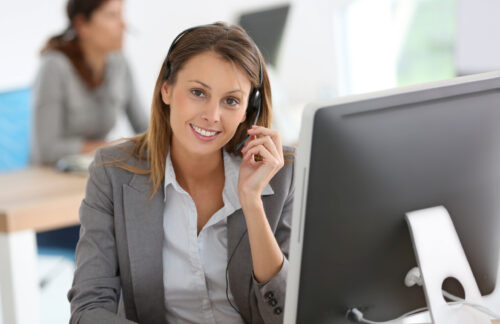 A smiling female SR22 insurance agent on the phone assisting a customer needing a Tennessee SR22 out-of-state insurance filing.