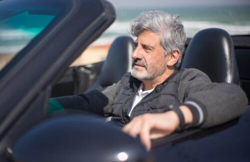 A middle-aged man with gray hair is driving a convertible with a lapsed Tennessee SR22 insurance policy.